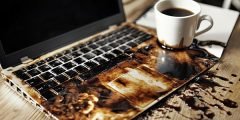 Notebook danificado com chocolate quente derramado sobre o teclado, ilustrando cobertura seguro notebook e tablet contra líquidos acidentais.