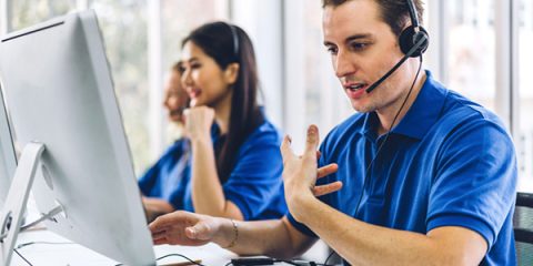 Central de atendimento com profissionais uniformizados prestando suporte técnico por telefone, representando o serviço emergencial 24h do seguro residencial.