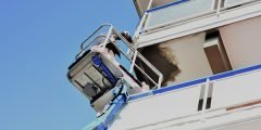 Equipamento realiza reparo na fachada de um prédio danificado, representando cobertura de danos a terceiros no seguro residencial