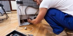 Técnico consertando geladeira em casa, ilustrando a cobertura seguro residencial para reparo de eletrodomésticos danificados.