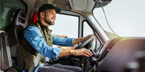 Homem sorridente dirigindo um caminhão, representando a conquista de um veículo pesado por meio de consórcio planejado, ideal para profissionais e empreendedores do transporte.