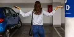 Mulher em um estacionamento olha para uma vaga vazia com os braços erguidos, transmitindo surpresa e preocupação, indicando que seu carro foi roubado. A imagem representa a importância da cobertura contra roubo e furto no seguro auto Pattini, que oferece proteção e indenização em casos como esse.