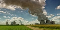 Instalação industrial emitindo fumaça densa em área rural, representando os riscos de poluição ambiental, contaminação do solo ou vazamentos súbitos cobertos pelo seguro de responsabilidade civil empresarial.